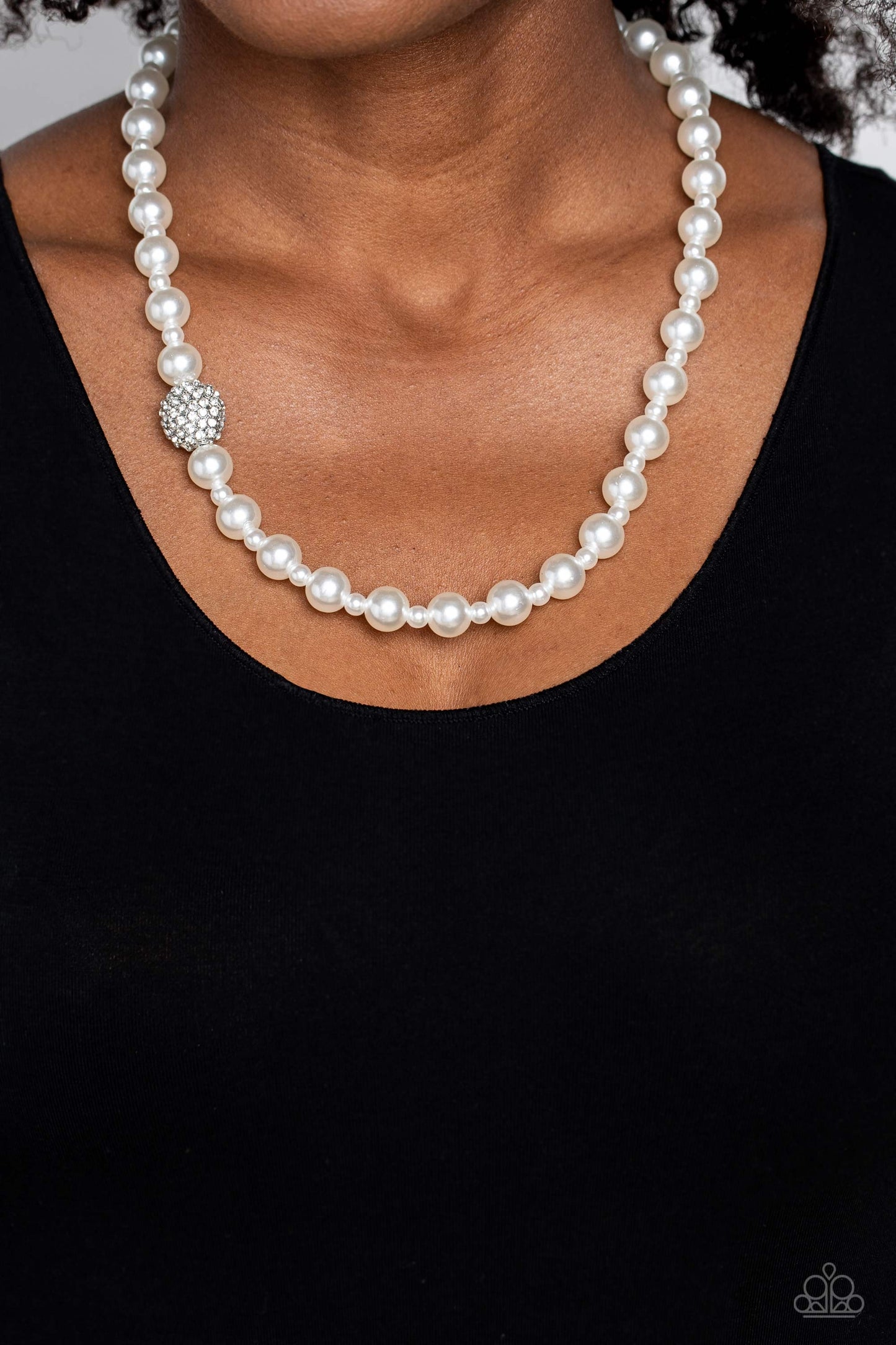 Paparazzi Accessories Countess Chic - White Strung along the entirety of an invisible wire, classic white pearls in varying sizes coalesce down the neckline for a refined finish. Adding to the elegant design, a sparkly white rhinestone-encrusted silver or