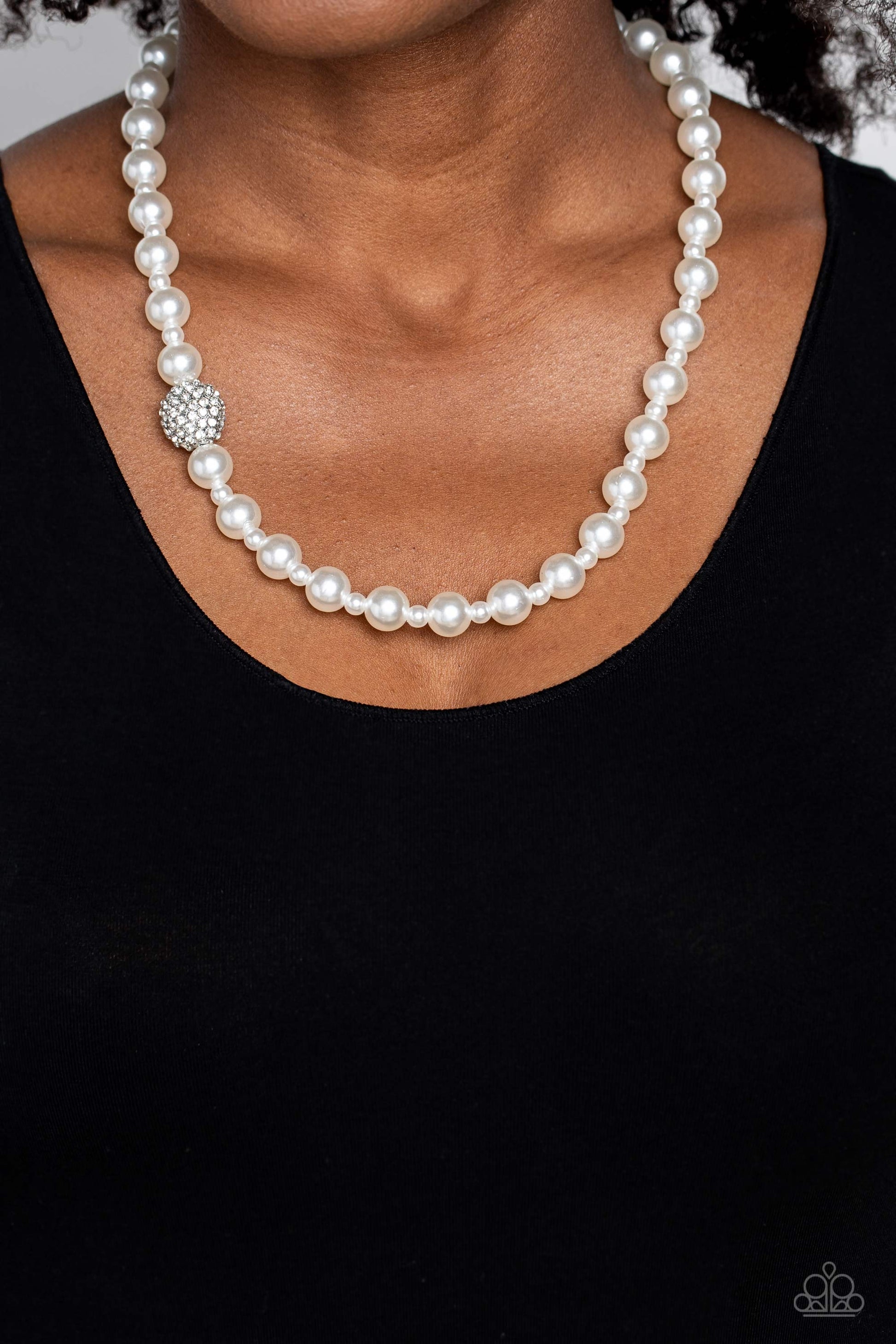 Paparazzi Accessories Countess Chic - White Strung along the entirety of an invisible wire, classic white pearls in varying sizes coalesce down the neckline for a refined finish. Adding to the elegant design, a sparkly white rhinestone-encrusted silver or