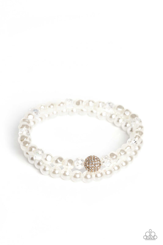 Paparazzi Accessories Countess Cutie - Gold A strand of classic white pearls and a strand of baroque white pearls coalesce around the wrist on stretchy bands for a refined finish. Infused along the baroque pearl strand, faceted crystal clear beads and a s