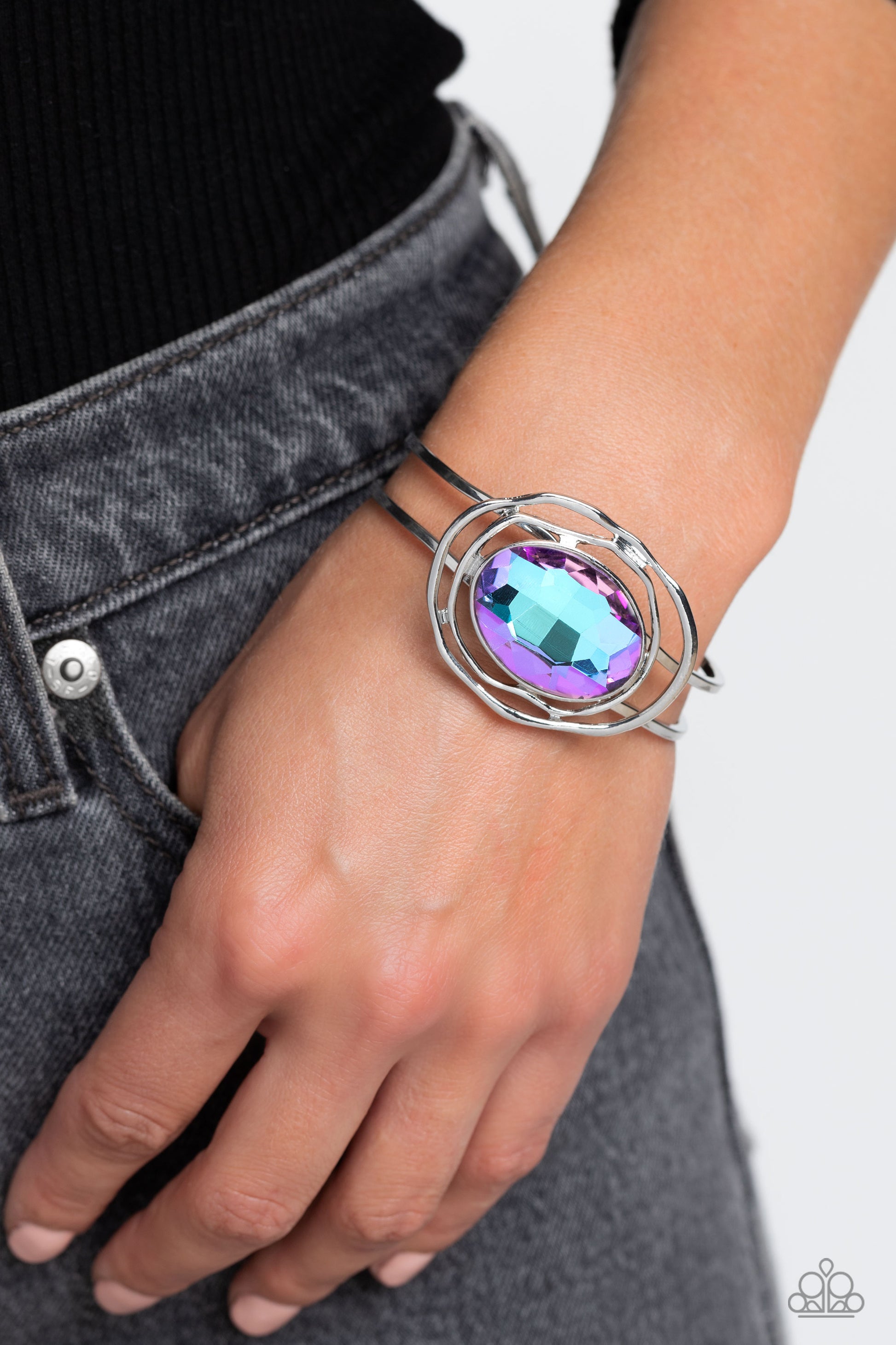 Paparazzi Accessories Substantial Sorceress - Purple Featured in the center of airy, shiny silver bands, an oversized, faceted purple oval gem rests atop the wrist for a dazzling pop of color. Warped, shiny silver rings seemingly float around the sparkly