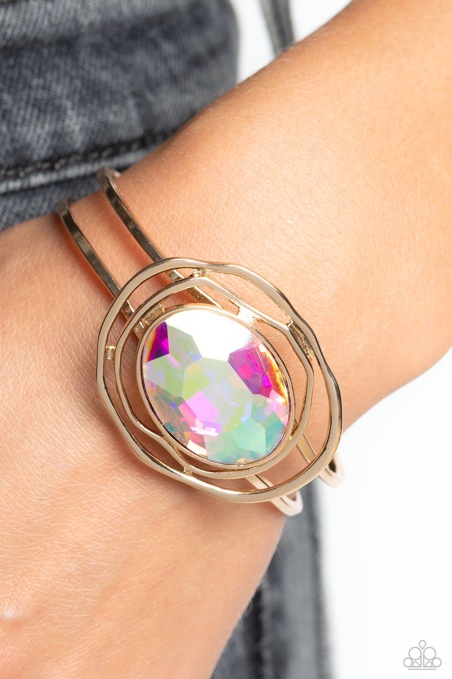 Paparazzi Accessories Substantial Sorceress - Multi Featured in the center of airy, shiny gold bands, an oversized, faceted iridescent oval gem rests atop the wrist for a dazzling pop of color. Warped, shiny gold rings seemingly float around the sparkly g