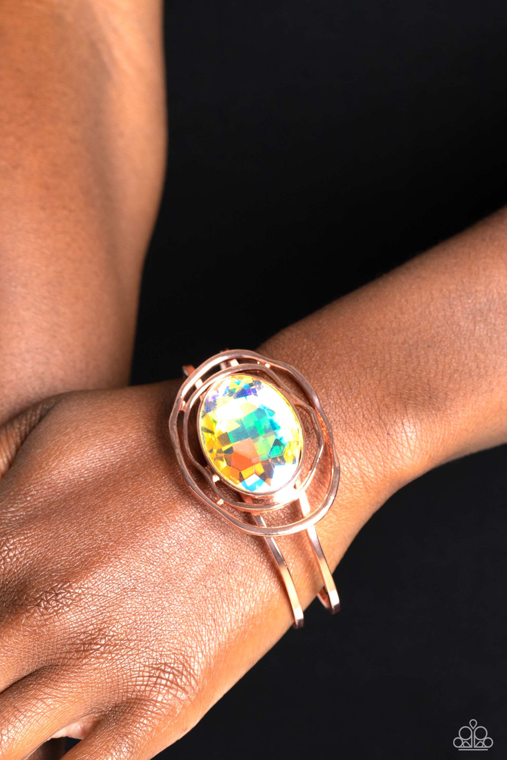 Paparazzi Accessories Substantial Sorceress - Copper Featured in the center of airy, shiny copper bands, an oversized, faceted iridescent oval gem rests atop the wrist for a dazzling pop of color. Warped, shiny copper rings seemingly float around the spar