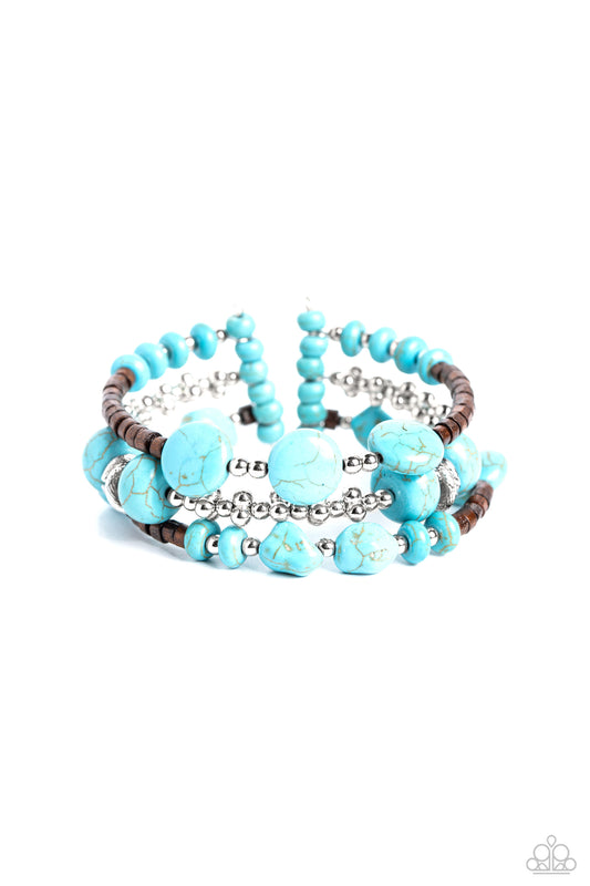 Paparazzi Accessories Operation Outdoors - Blue An earthy collection of brown wooden beads, classic silver beads and accents, and turquoise stones in varying sizes are threaded along invisible wires to create three bands that arc across the wrist. The ban