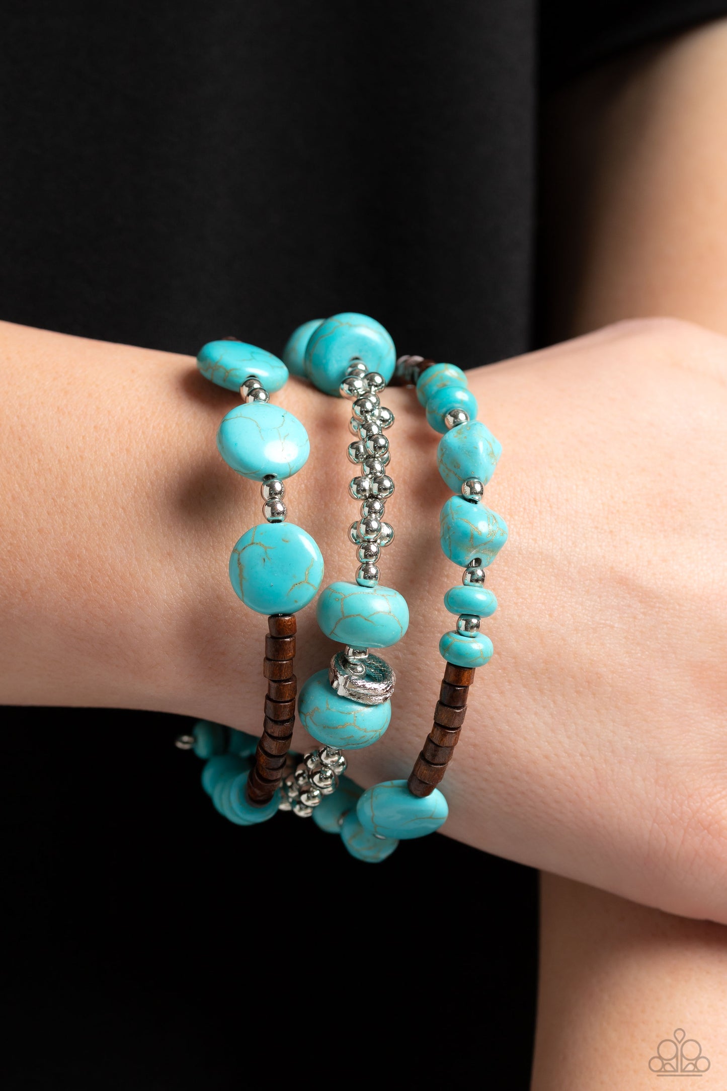 Paparazzi Accessories Operation Outdoors - Blue An earthy collection of brown wooden beads, classic silver beads and accents, and turquoise stones in varying sizes are threaded along invisible wires to create three bands that arc across the wrist. The ban