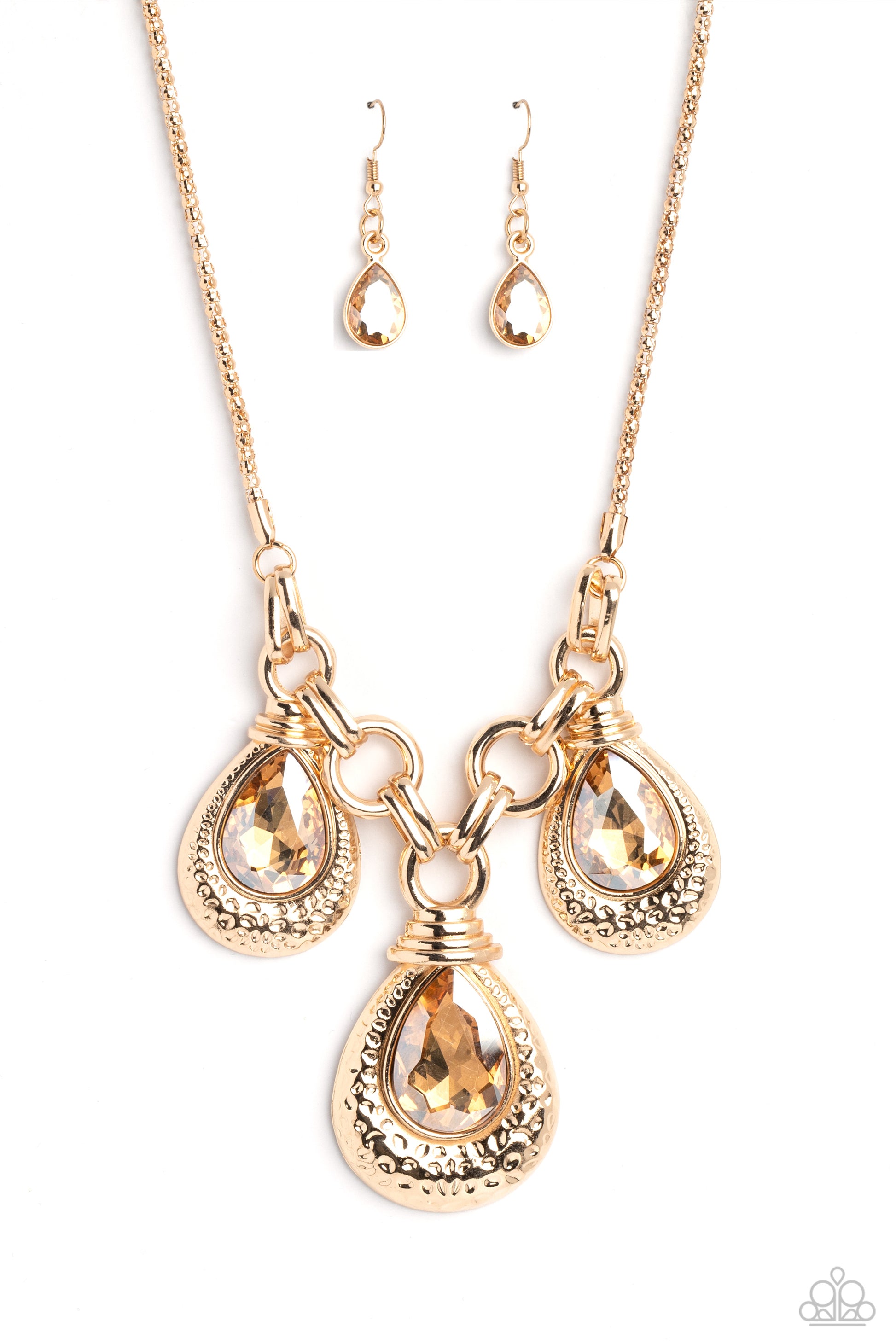 Paparazzi Accessories Built Beacon - Gold Oversized links of gold are artfully interlocked, laying the groundwork for a dynamic display of industrial grit. A trio of oversized champagne, faceted, teardrop gems drips from the chainlinks above, each set ins