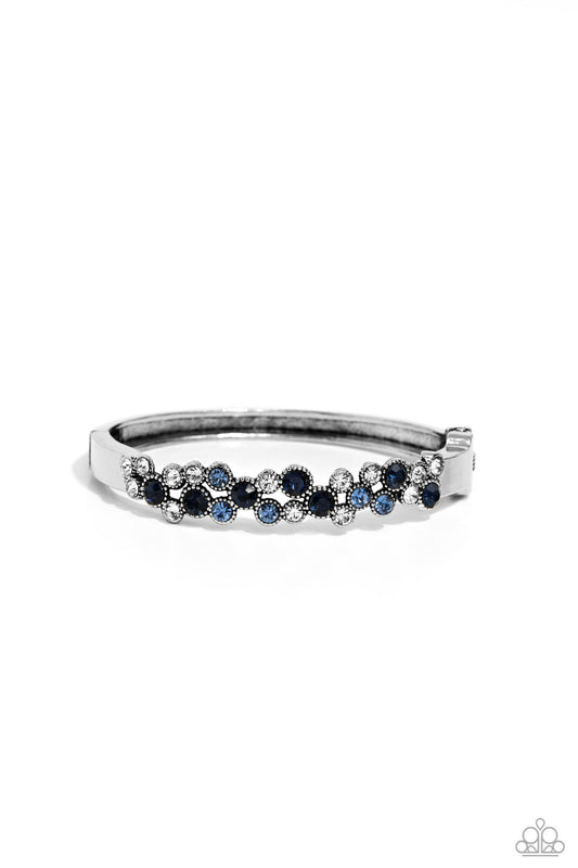Paparazzi Accessories Big City Bling - Blue Featuring a crisscross pattern, a studded, framed collection of gems in varying sizes in shades of blue and white coalesce the top of a thick, silver bracelet for a pop of shimmery color atop the wrist. Features