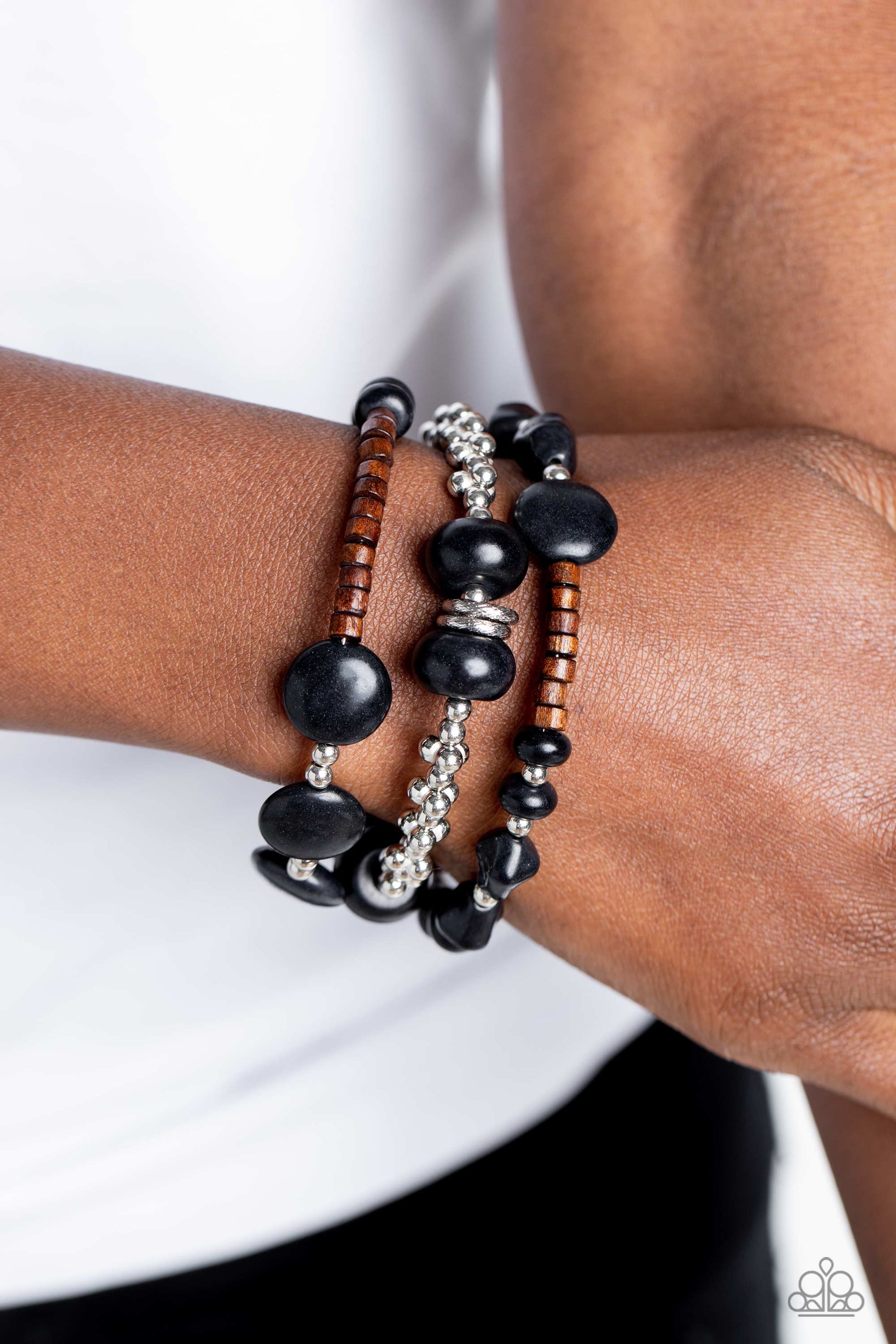 Paparazzi Accessories Operation Outdoors - Black An earthy collection of brown wooden beads, classic silver beads and accents, and black stones in varying sizes are threaded along invisible wires to create three bands that arc across the wrist. The bands