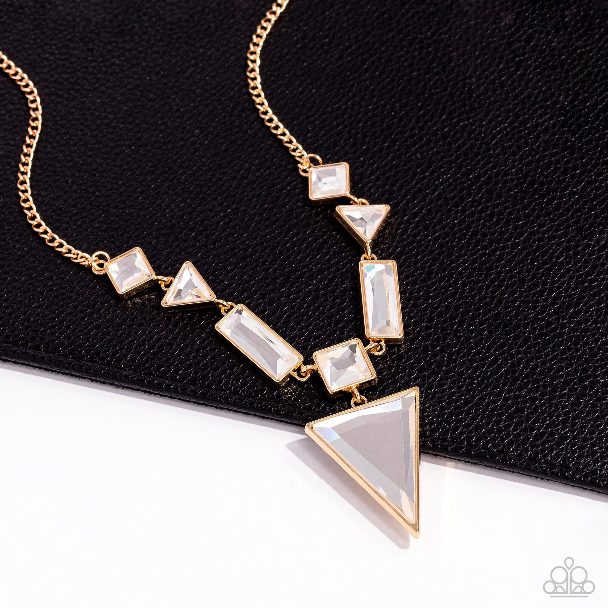 Paparazzi Accessories Fetchingly Fierce - Gold An array of glassy white gems are chiseled into geometric shapes and pressed into shimmery gold frames. The angular display falls to a dramatic point at the center, where a square-cut gem anchors an upside-do