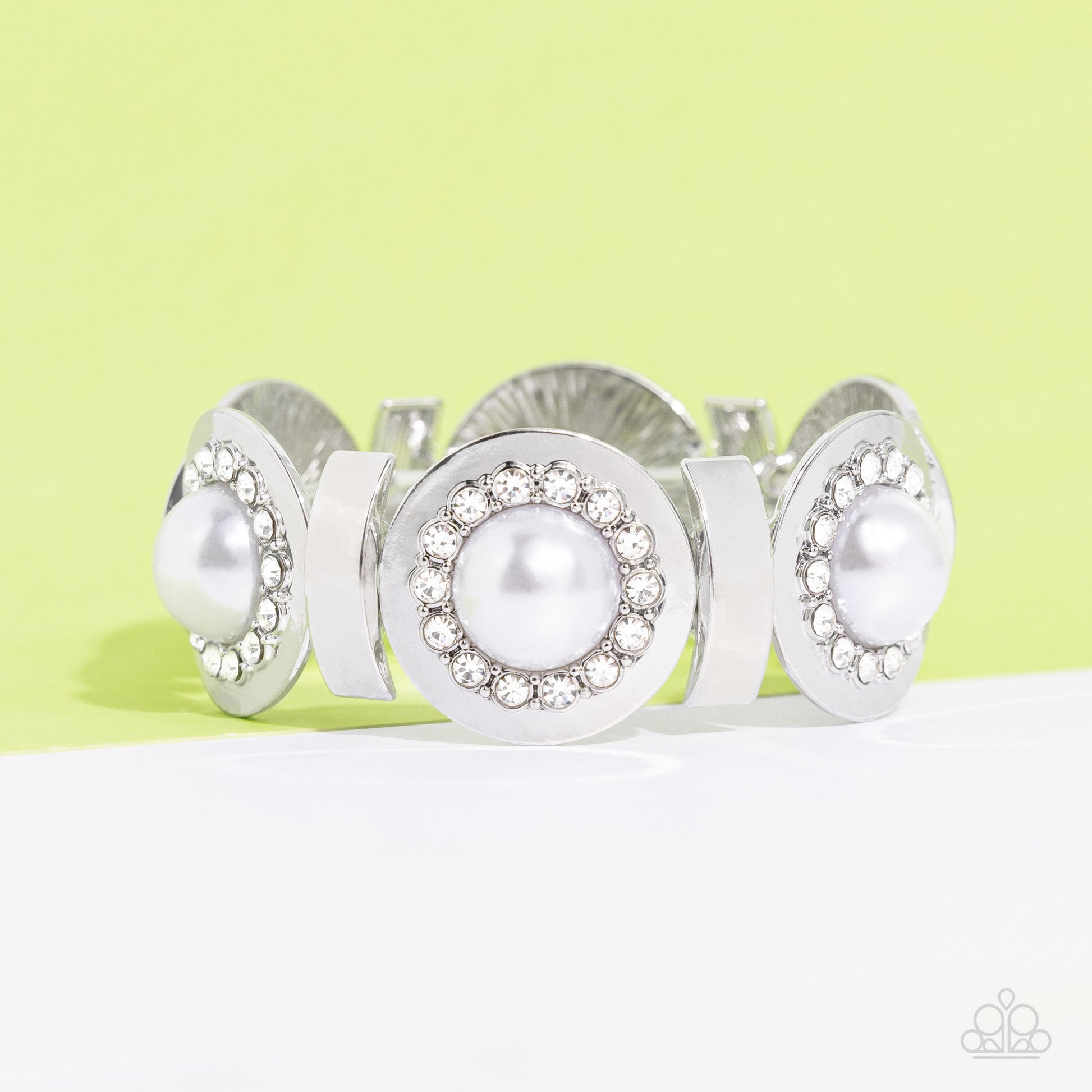 Paparazzi Accessories Summer Serenade - White Concaved silver frames, with an embossed row of white gems, encircle an oversized pearl center creating refined flowers. Sleek curls of silver alternate between the bejeweled flowers for additional shine and c