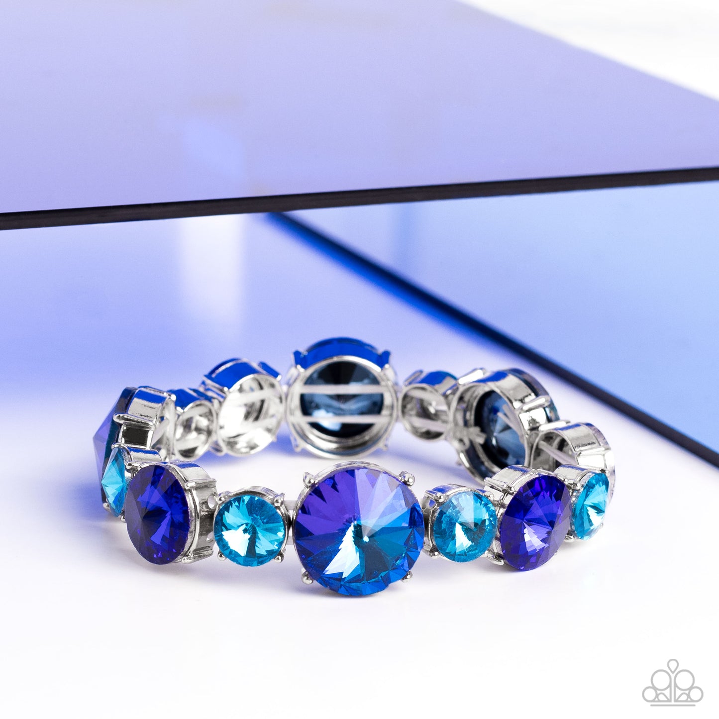 Paparazzi Accessories Refreshing Radiance - Blue Pressed in silver-pronged frames, vibrant blue gems in varying sizes and shades alternate along stretchy bands around the wrist, creating a colorful pop of color. The larger blue gems feature a stellar UV s