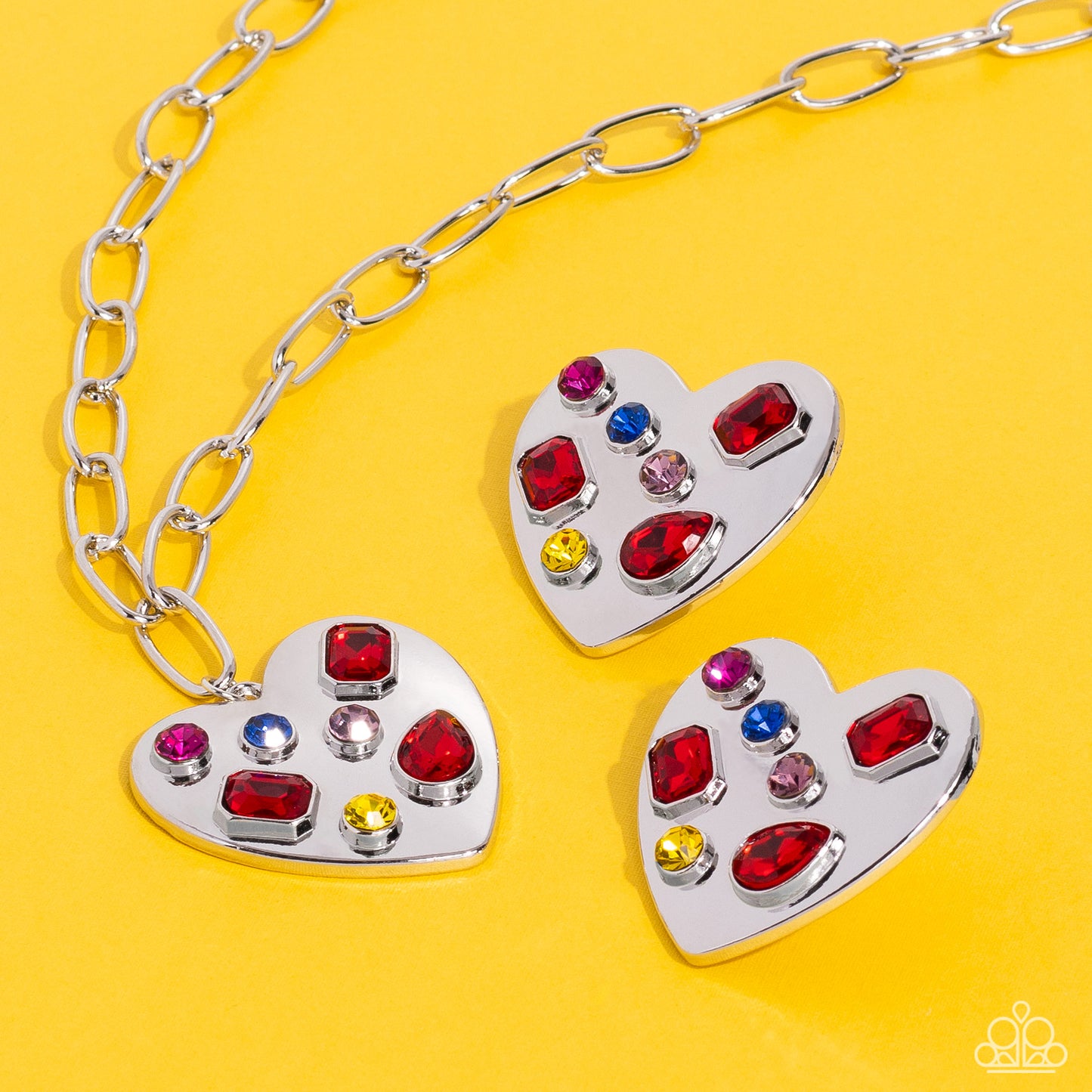 Paparazzi Accessories Relationship Ready - Red Brushed with shimmery pink, yellow, blue, and red round, teardrop and emerald-cut gems, an oversized, high-sheen silver heart frame rests against the ear for a dazzling finish. Earring attaches to a standard