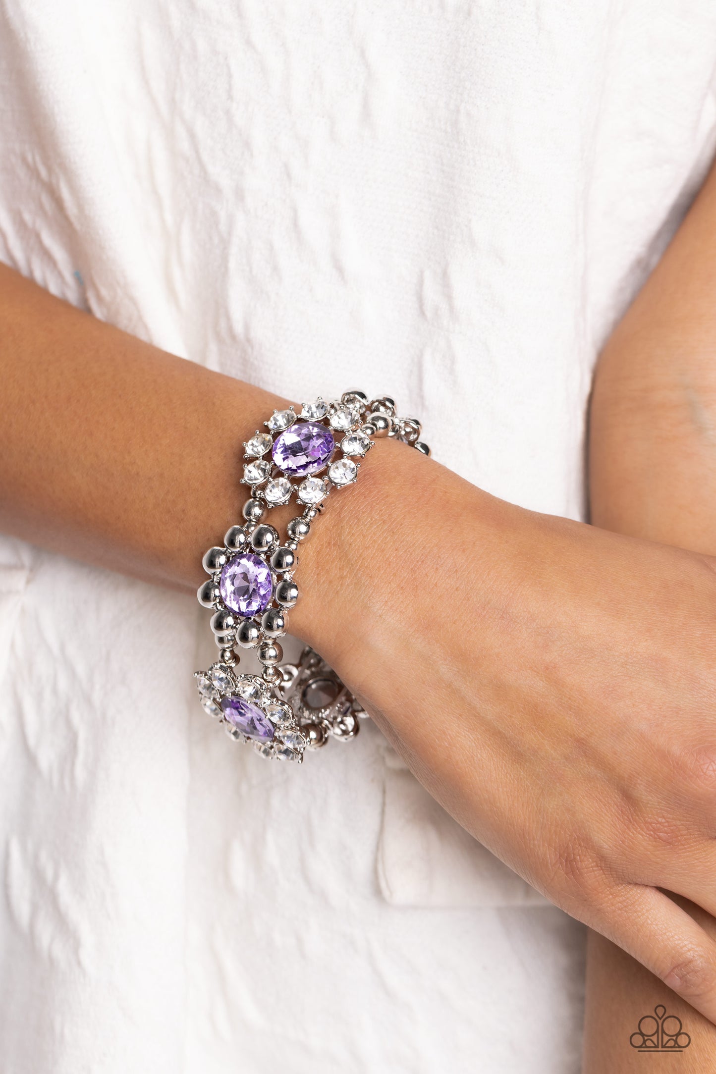 Paparazzi Accessories Pact of Petals - Purple Scattering around faceted purple rhinestones, pronged white-gem petals and faceted silver beaded petals alternate along stretchy bands resulting in regally refined floral frames that wrap around the wrist. Sol