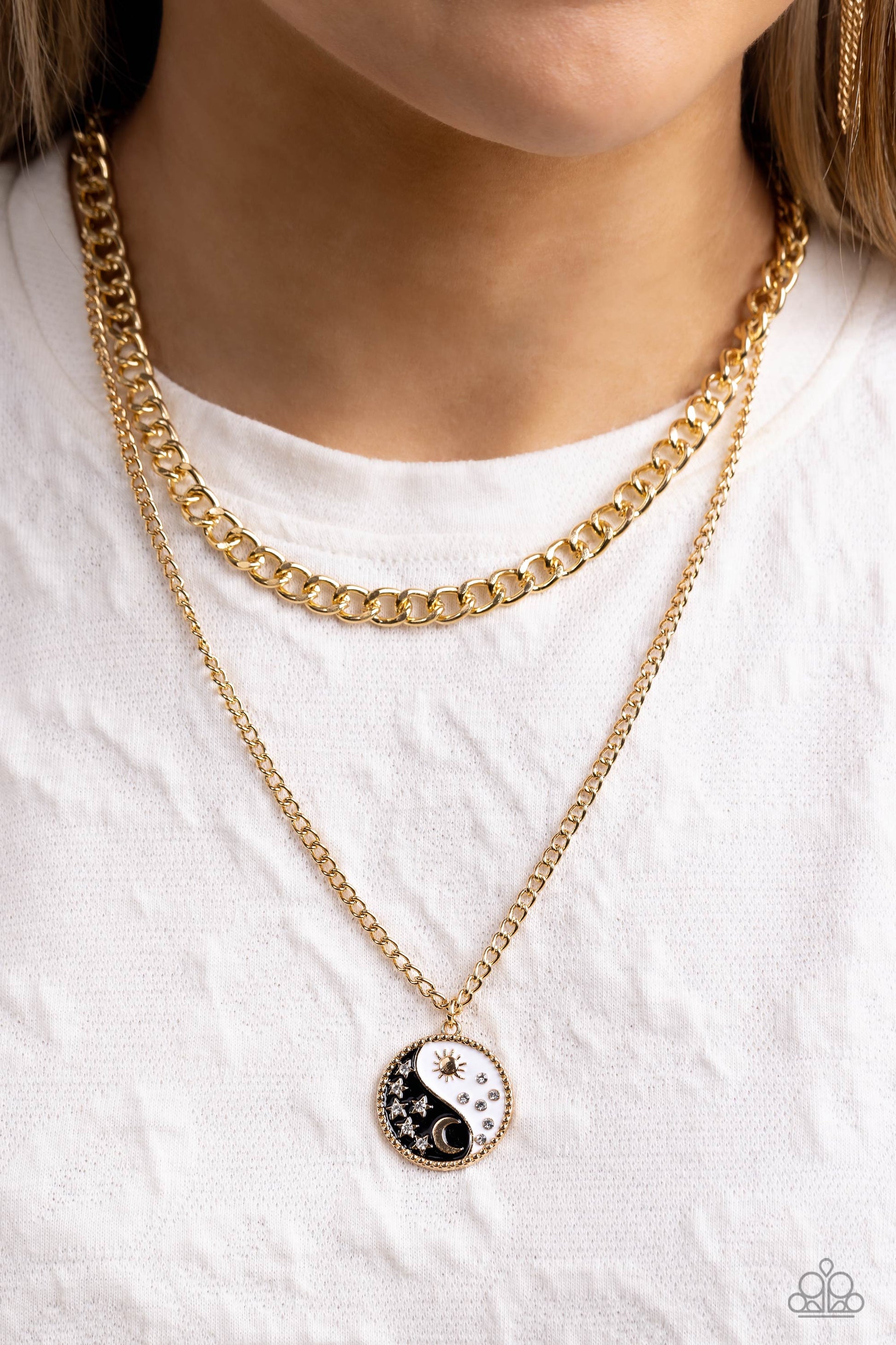 Paparazzi Accessories Night and Day - Black Featuring a yin-yang design, a gold moon with rhinestone-dusted stars rests on the black curve, while a gold sun with rhinestone beams of light rests on the white curve for a balanced, studded display down the n