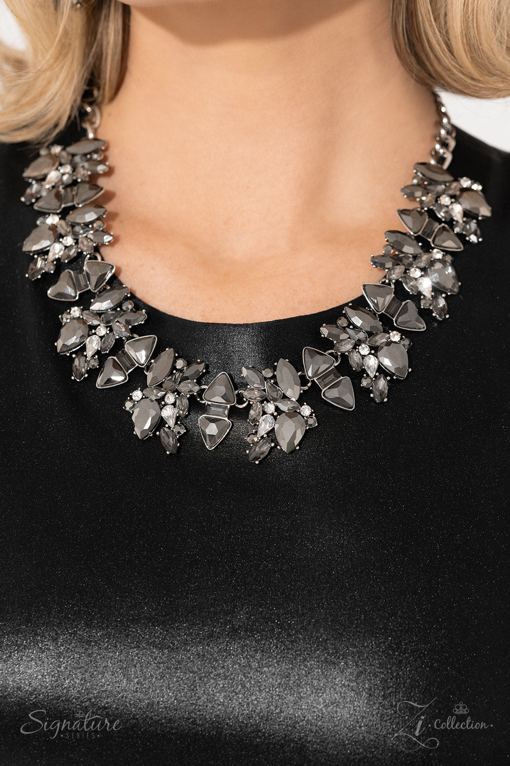 Paparazzi Accessories The J.J. Smoldering clusters of gleaming hematite and smoky sparkle erupt into an edgy exhibition along the collar. Each cluster is shaped by teardrop- and marquise-cut gems, exaggerated by pronged fittings as they collide with class