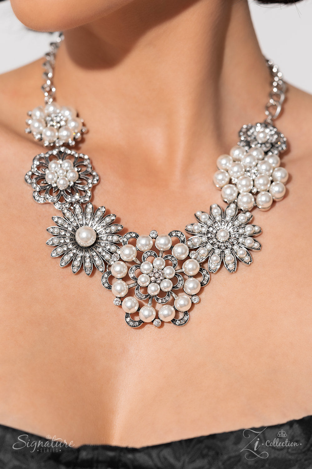 Paparazzi Accessories The Raven Polished white pearls and brilliant white rhinestones bloom atop a framework of silver, forming seven unique flowers adorned in dizzying detail. Each flower features a unique centerpiece encircled by silver petals lined wit
