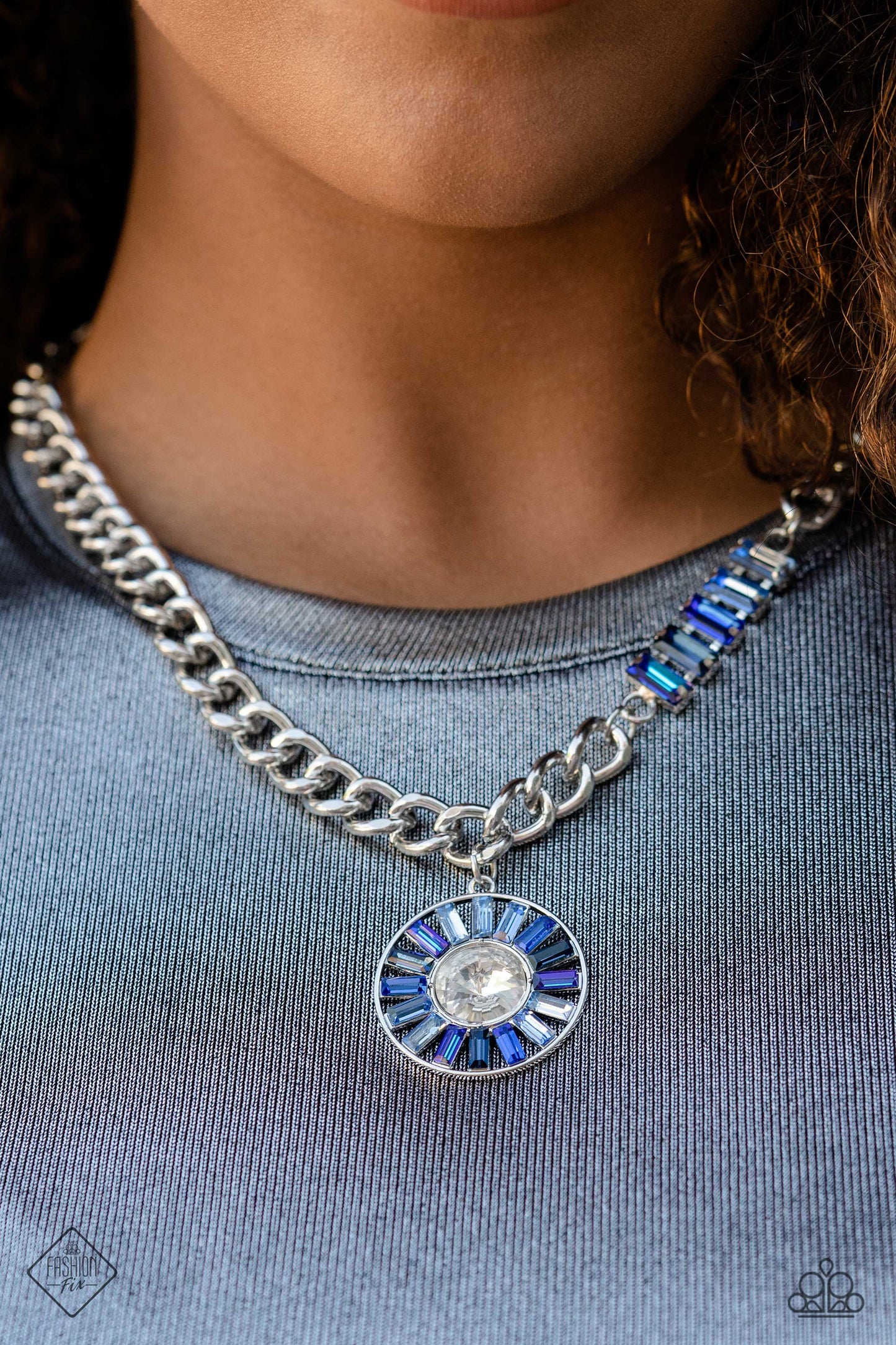 Paparazzi Accessories Tiered Talent - Blue An exaggerated white gem is encircled by a collection of emerald-cut gems in varying shades of blue, creating a hypnotic pendant that swings from a thick silver curb chain. Five additional emerald-cut gems in the