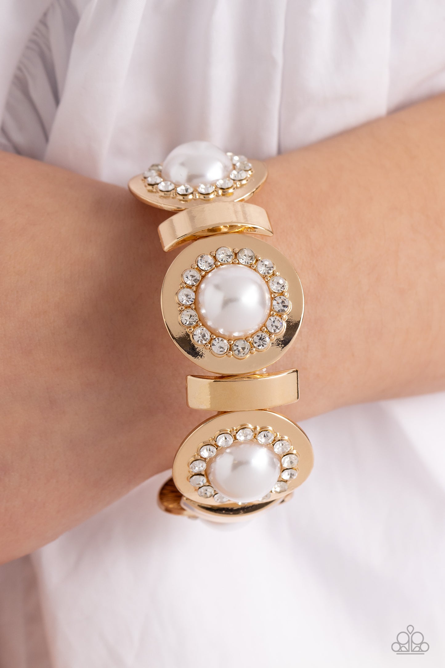 Paparazzi Accessories Summer Serenade - Gold Concaved gold frames, with an embossed row of white gems, encircle an oversized pearl center creating refined flowers. Sleek curls of gold alternate between the bejeweled flowers for additional shine and capric