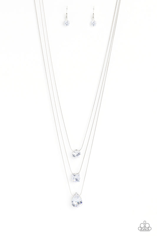 Paparazzi Accessories Lustrous Layers - White Featuring a subtle iridescent finish, exaggerated, faceted round, square, and teardrop gems layer down the chest from three sleek silver dainty chains, in a refined fashion. Features an adjustable clasp closur