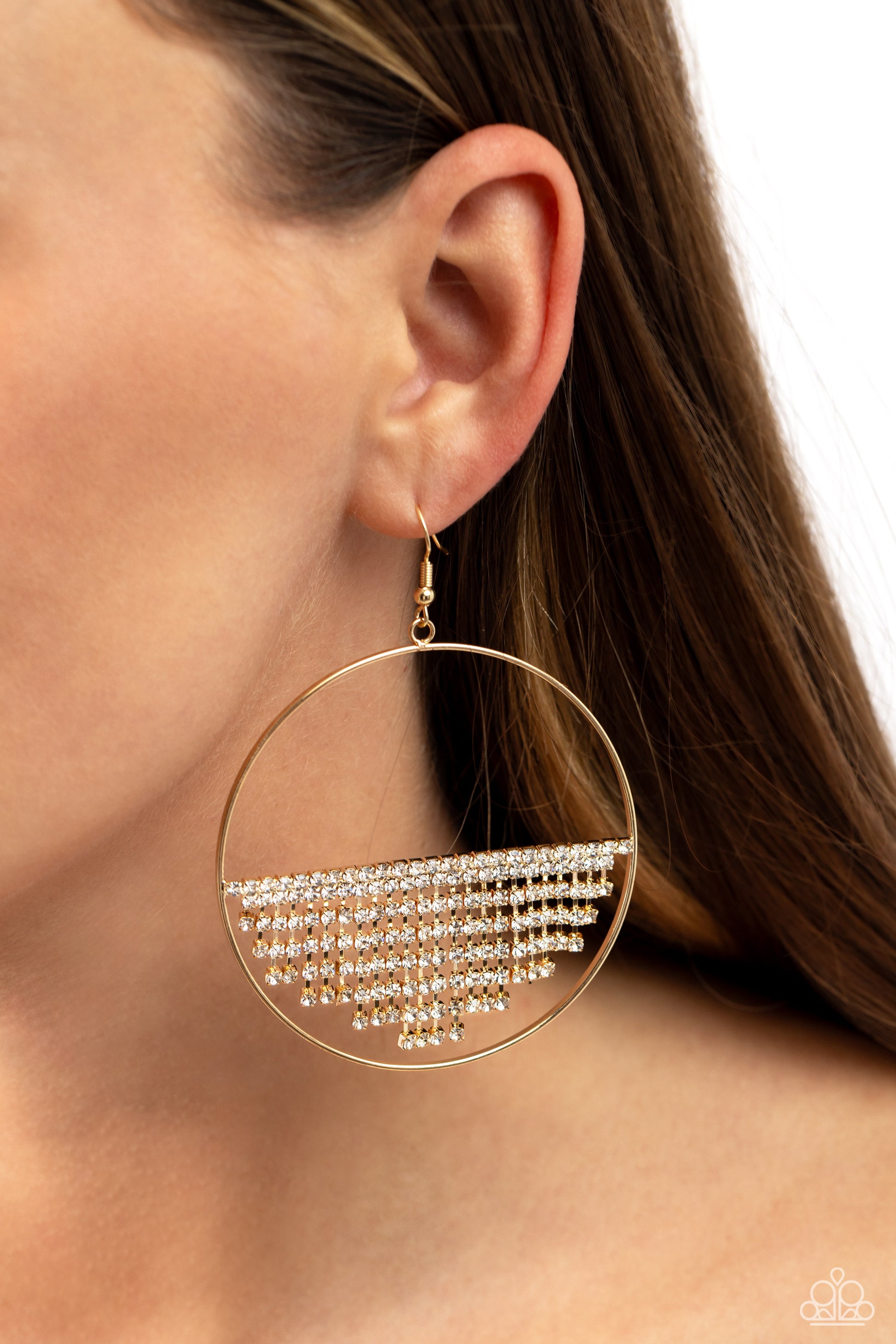 Paparazzi Accessories Fierce Fringe - Gold A curtain of white rhinestones is stretched between the edges of a skinny, oversized gold hoop, creating a shimmering display. The rhinestones taper towards the center as they sway and cascade, adding sparkly mov