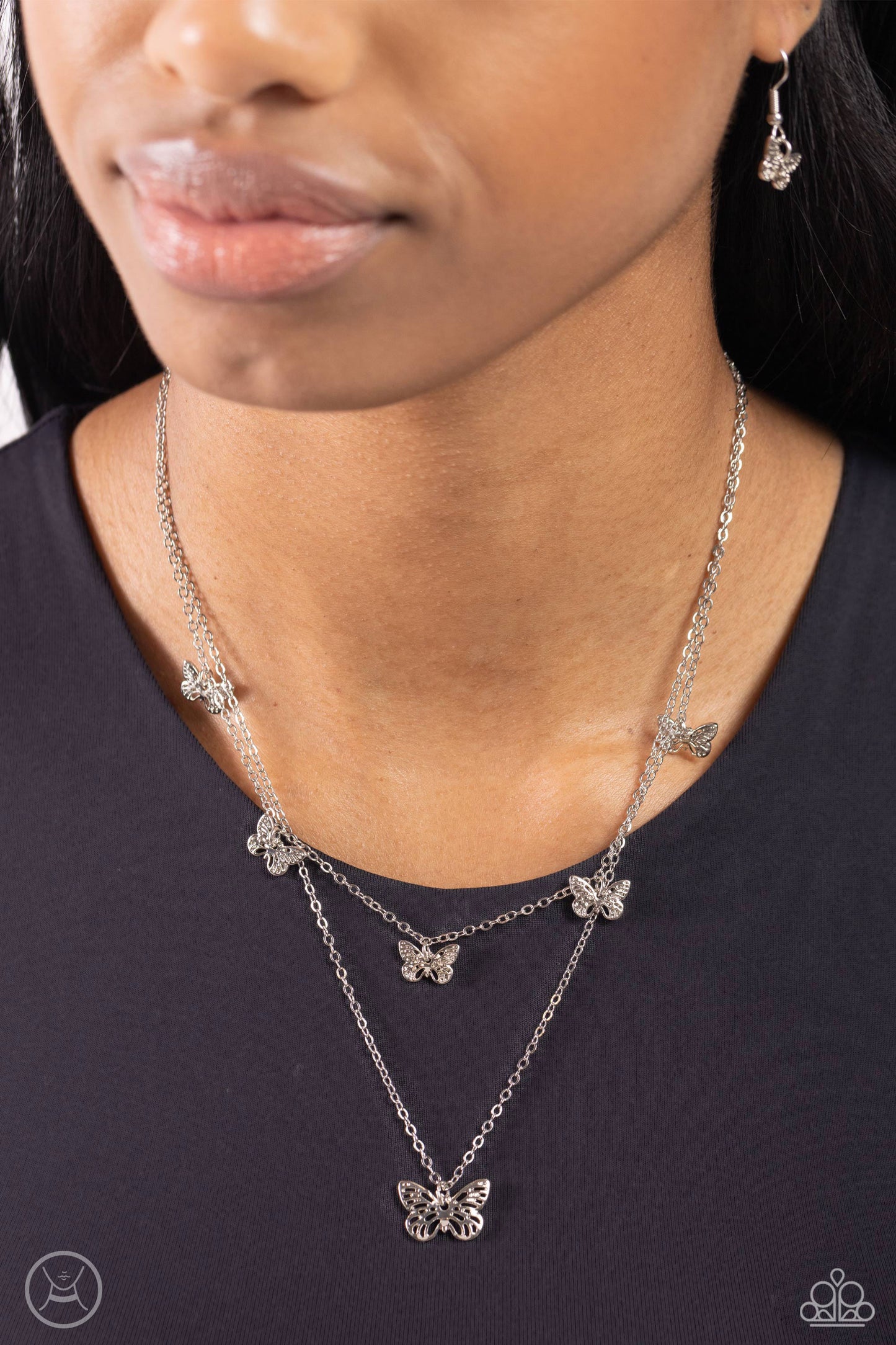Paparazzi Accessories Butterfly Beacon - Silver Floating along a dainty silver chain, a collection of ornate silver butterflies coalesces down the neckline for a whimsical finish. A larger silver butterfly, featuring the same ornate detail swings below th