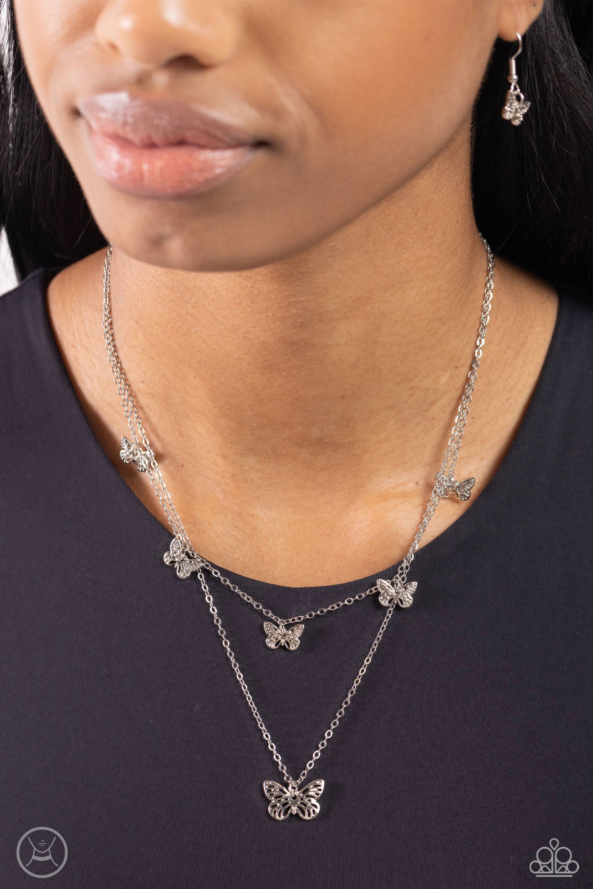 Paparazzi Accessories Butterfly Beacon - Silver Floating along a dainty silver chain, a collection of ornate silver butterflies coalesces down the neckline for a whimsical finish. A larger silver butterfly, featuring the same ornate detail swings below th