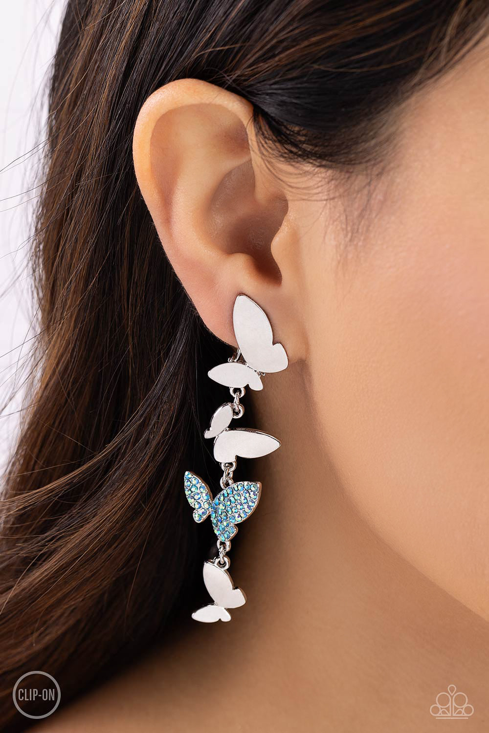 Paparazzi Accessories Flying Flashy - Blue *Clip-On Three butterflies with high-sheen silver wings and one blue iridescent-encrusted butterfly flutter down the ear, creating a free-spirited lure. Each butterfly swings in whimsical asymmetry, creating the