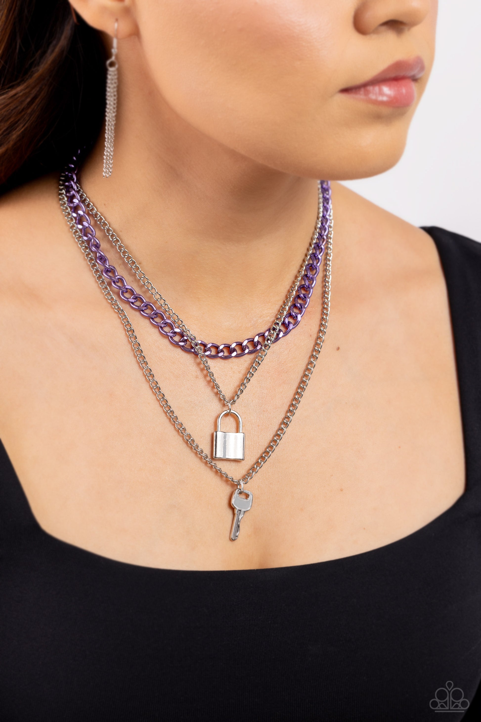 Paparazzi Accessories Locked Labor - Purple A sleek silver lock and silver key trickle from the bottoms of glistening silver chains down the chest, creating industrial layers. A purple curb chain hangs above the pendants for a touch of colorfully gritty s