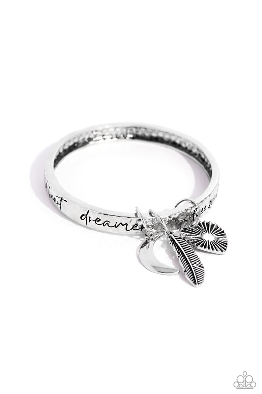 Paparazzi Accessories Free-Spirited Fantasy - Silver A hammered silver bangle featuring a textured feather, sleek crescent moon, and textured heart charms wraps around the wrist for an artisan-inspired fashion. Painted in a black hue, the phrases “free sp