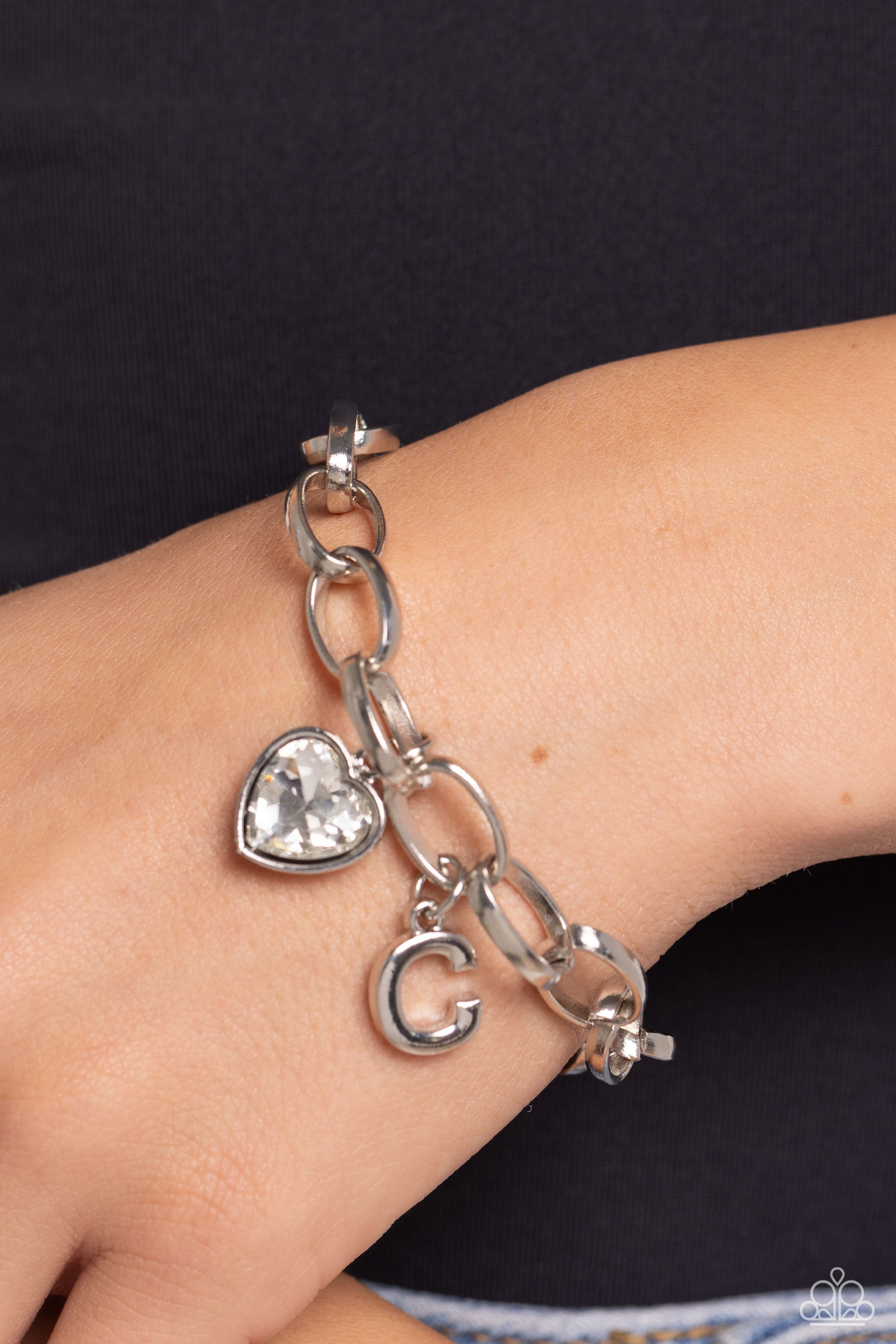 Paparazzi Accessories Guess Now Its INITIAL - White - C A simple collection of silver charms — including a white rhinestone heart pressed in a silver frame and a sleek letter "C" — dance from a chunky silver chain around the wrist, creating a sentimental