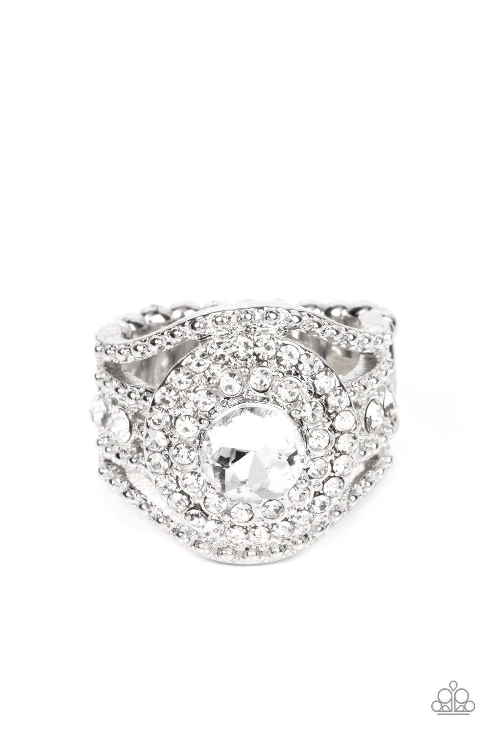 Paparazzi Accessories Understated Drama - White Bordered in stacked rings of glassy white rhinestones, a brilliant white gem sits atop layers of silver studded bars that swoop and stack into blinding bands across the finger. Features a stretchy band for a