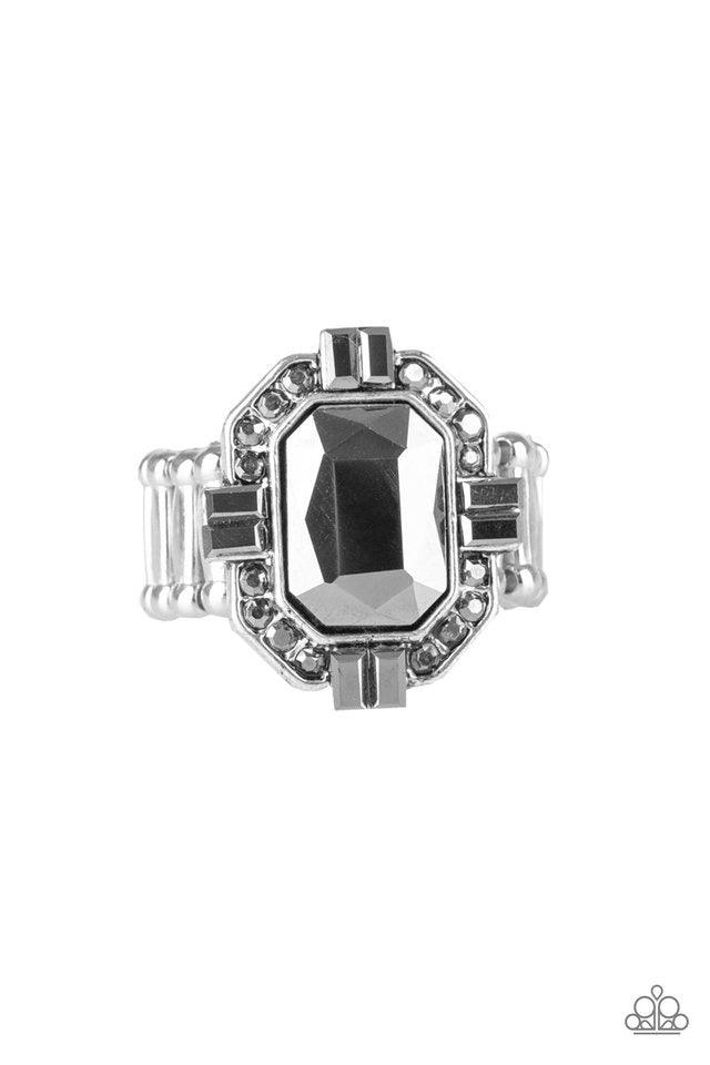 Paparazzi Accessories Outta My Way ~Silver Featuring a regal emerald-style cut, a faceted hematite gem is pressed into the center of a silver frame radiating with smoky hematite rhinestones. Features a stretchy band for a flexible fit.