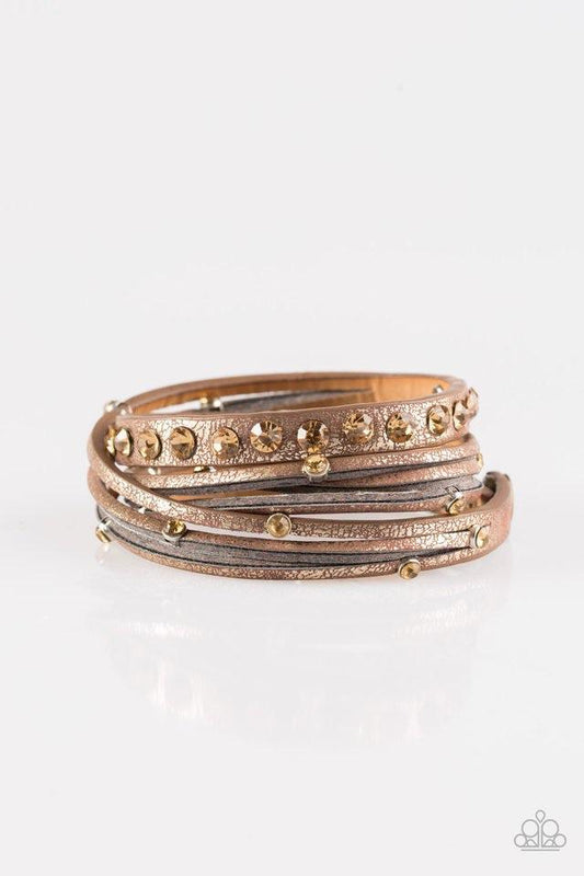 Paparazzi Accessories CATWALK It Off ~Brown Dusted in a golden shimmer, a skinny strip of brown leather is spliced into sections of glittery strands. Infused with golden rhinestones, the elongated band double wraps around the wrist for a fierce one-of-a-k