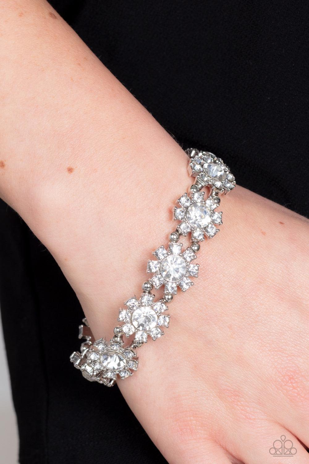 Paparazzi Accessories Premium Perennial - White Separated by pairs of dainty silver beads, rhinestone-dotted petals bloom from oversized white rhinestone centers along stretchy bands around the wrist for a flirtatious floral fashion. Sold as one individua