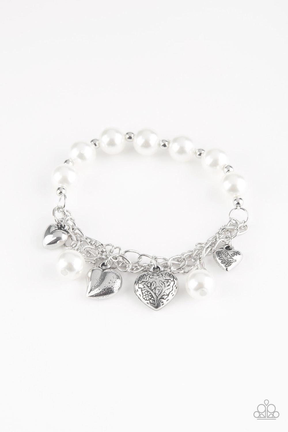 Paparazzi Accessories More Amour - White Attached to a section of shimmery silver chain, pearly white and dainty silver beads are threaded along a stretchy band. Mismatched silver heart charms swing from the glistening chain, creating a flirty fringe. Jew