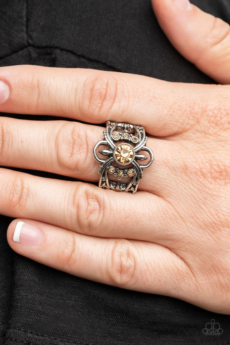 Paparazzi Accessories We Wear Crowns Here - Brown A solitaire golden topaz rhinestone is flanked by stacked rows of dainty golden topaz rhinestones inside swooping silver bars dotted in antiqued silver studs, resulting in a refined sparkle atop the finger