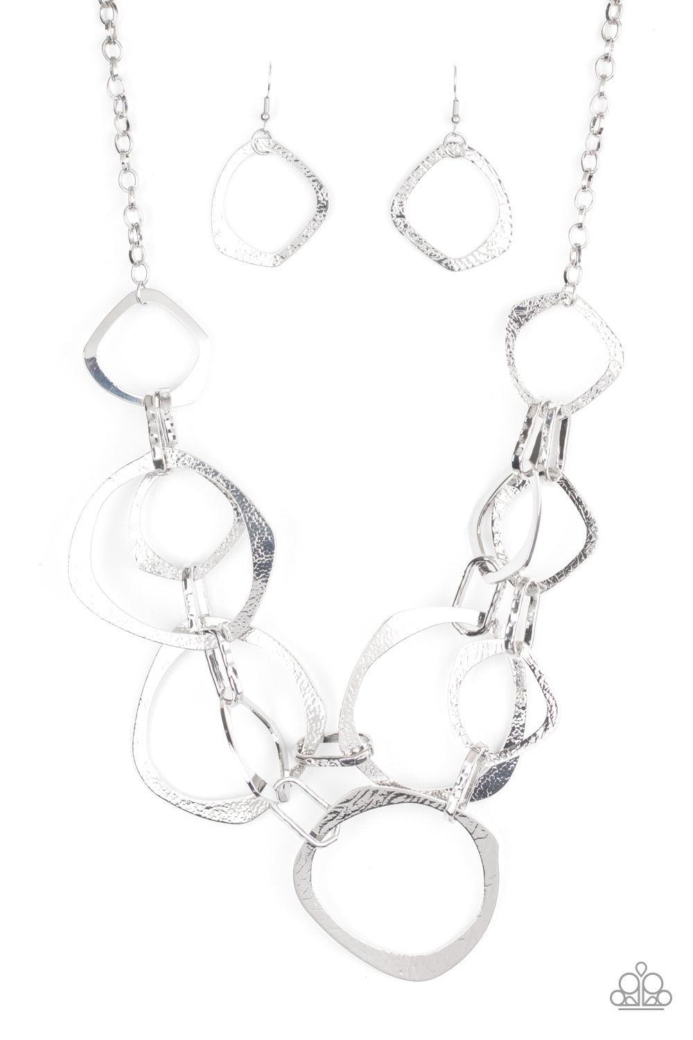 Paparazzi Accessories Salvage Yard - Silver Hammered in shimmery detail, oversized asymmetrical silver rings and gritty silver links boldly link below the collar in two dramatic rows for a sassy industrial look. Features an adjustable clasp closure. Sold