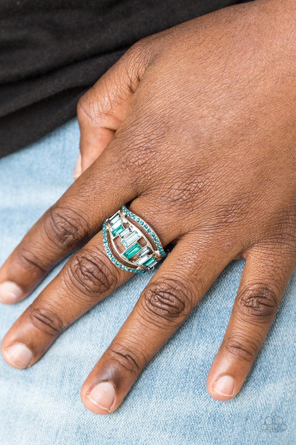 Paparazzi Accessories Treasure Chest Charm - Blue Blue rhinestone encrusted bands flank a row of emerald cut glass beads in shades of blue for a regal look. Features a stretchy band for a flexible fit. Jewelry