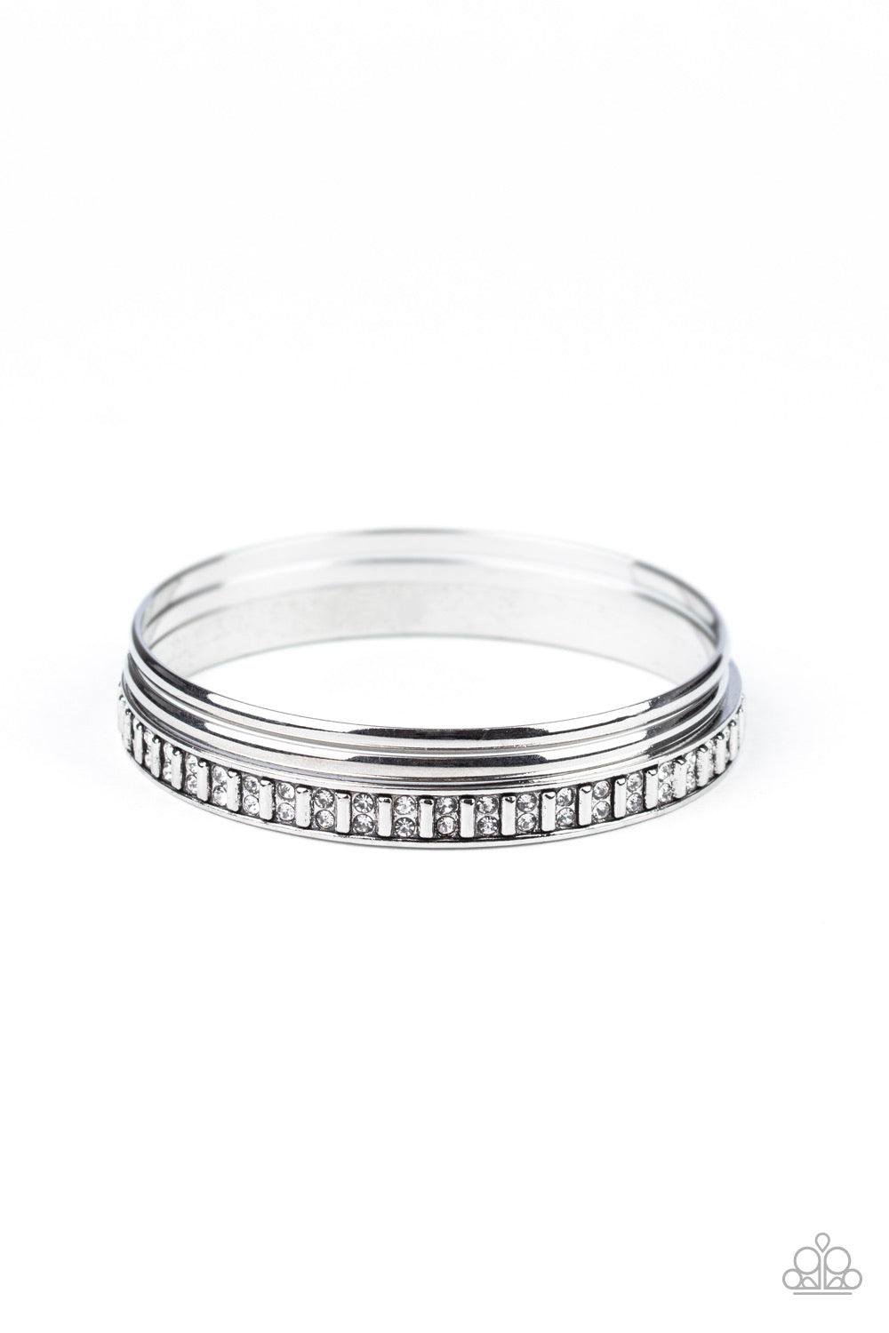 Paparazzi Accessories Flawless Flaunter - White Two classic silver bangles join a thick silver bangle that has been encrusted in pairs of dainty white rhinestones and rectangular silver beading for an edgy refinement. Jewelry