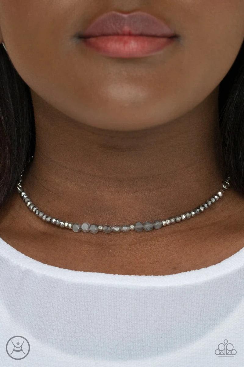 Paparazzi Accessories Space Odyssey - Silver A dainty collection of mismatched silver beads, hematite rhinestones, and smoky crystal-like accents are threaded along an invisible wire around the neck for a stellar look. Features an adjustable clasp closure