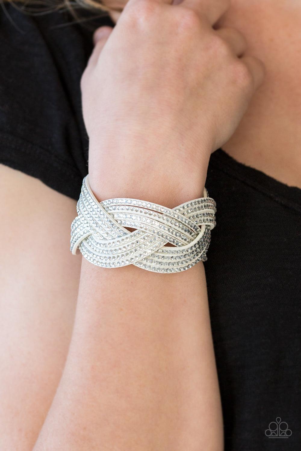 Paparazzi Accessories Big City Shimmer - White Glassy white rhinestones are encrusted along crisscrossing strands of white suede, creating bold shimmer around the wrist. Features an adjustable snap closure. Sold as one individual bracelet. Jewelry