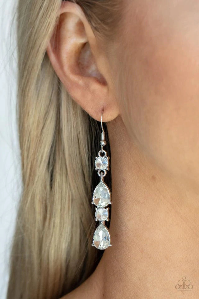 Paparazzi Accessories Raise Your Glass to Glamorous - White A glamorous collection of brilliant white teardrop and round rhinestones encased in classic silver pronged fittings stack together creating an irresistibly refined lure. Earring attaches to a sta