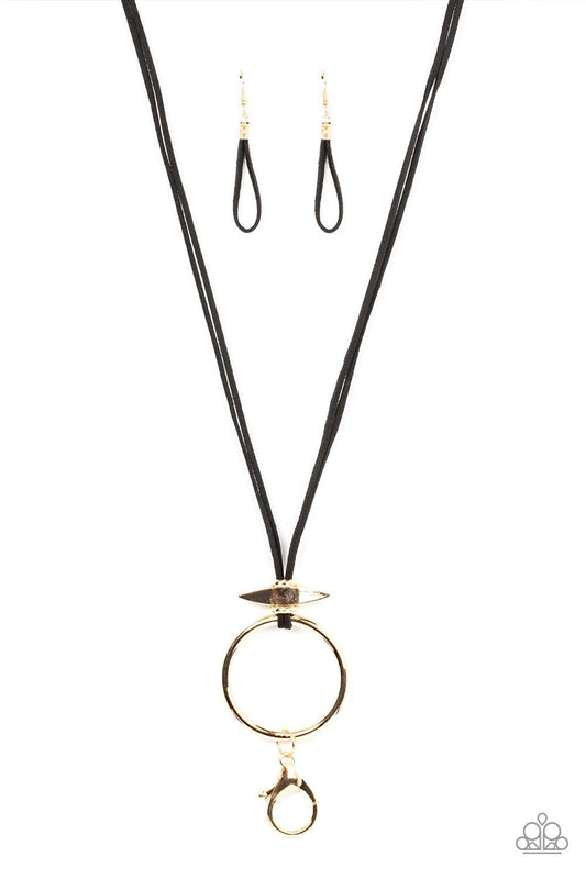 Paparazzi Accessories Noticeably Nomad - Gold *Lanyard Flanked by dainty gold rings, a marquise shaped gold bead glides along lengthened strands of black suede, holding in place an oversized gold ring at the bottom for an artisan inspired fashion. A gold
