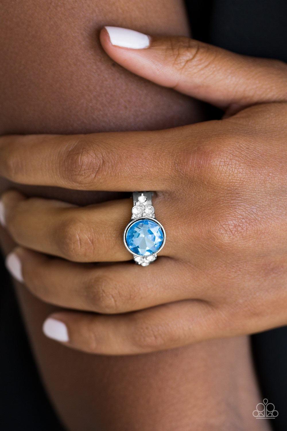 Paparazzi Accessories Poshly Pampered - Blue An oversized blue rhinestone is pressed into the center of a dainty silver band radiating with glassy white rhinestones for a glamorous look. Features a dainty stretchy band for a flexible fit. Jewelry