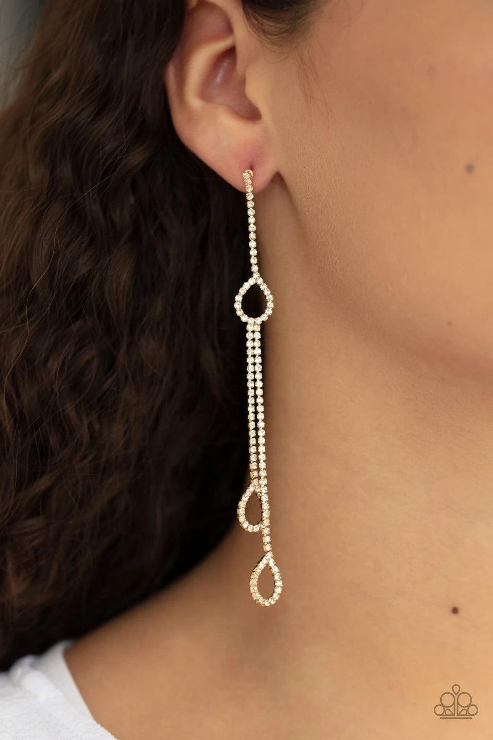 Paparazzi Accessories Chance of REIGN - Gold Dainty strands of glittery white rhinestones stream from the bottom of a teardrop frame. Matching teardrop frames drip from the bottom of glittery tassels for a timeless finish. Earring attaches to a standard p