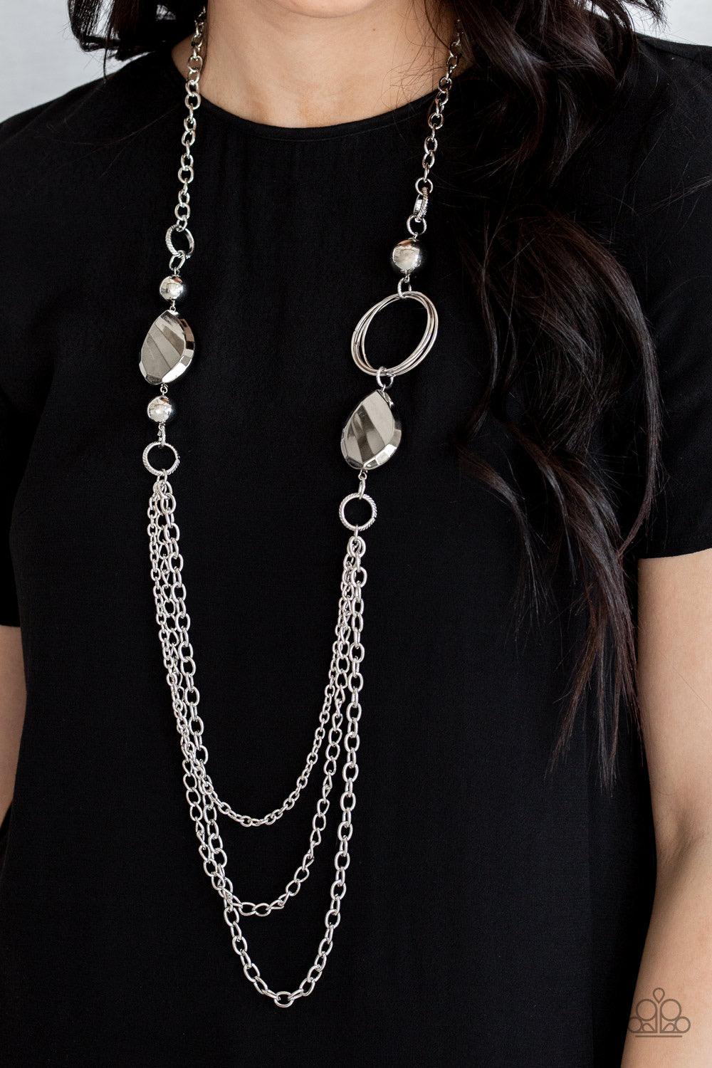 Paparazzi Accessories Rebels Have More Fun - Silver A mismatched collection of oversized silver beads, hoops, and textured silver accents give way to layers of antiqued silver chains down the chest for an edgy industrial look. Features an adjustable clasp