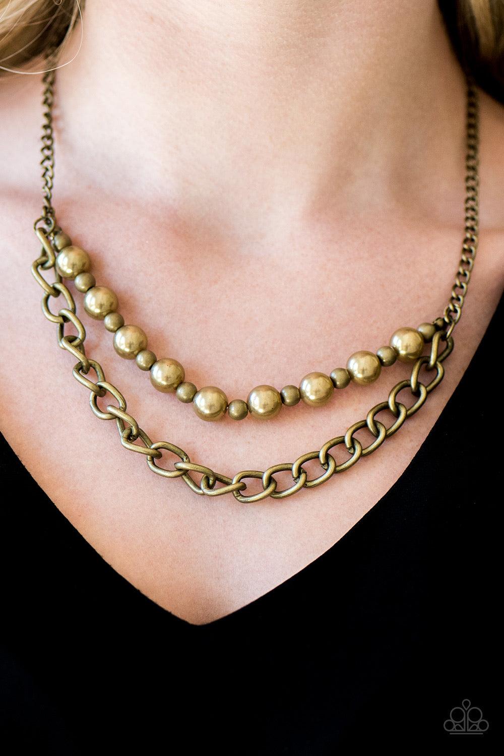 Paparazzi Accessories Glam and Grind - Brass Pearly brass and rustic brass beads are threaded along a skinny wire. The pearly beading gives way to a bold strand of brass chain, creating edgy layers below the collar. Features an adjustable clasp closure. S