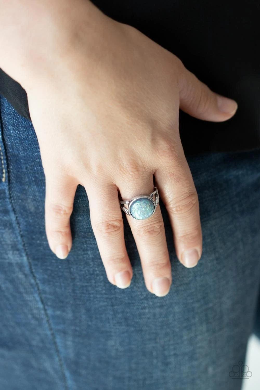 Paparazzi Accessories Glitter Grove - Silver An opalescent bead flecked with shimmering iridescent glitter is encased in a simple round silver frame creating a dazzling centerpiece atop the finger. Features a dainty stretchy band for a flexible fit. Sold
