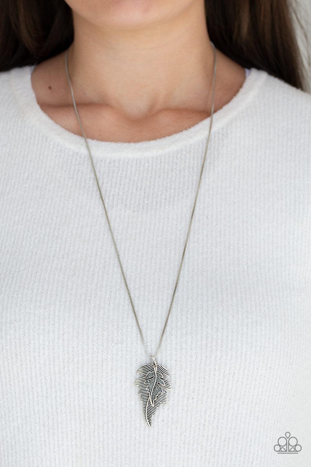 Paparazzi Accessories Enchanted Meadow - Silver Encrusted in smoky rhinestones and stacked with linear textures, feathery silver leaf pendants swing from the bottom of a lengthened silver chain for a seasonal flair. Features an adjustable clasp closure. J