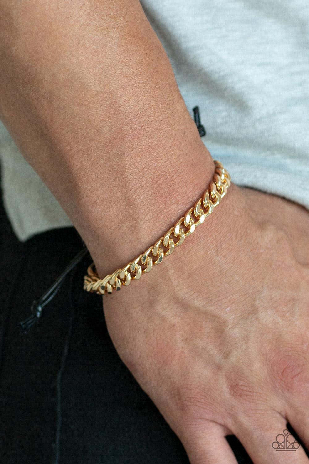 Paparazzi Accessories Throwdown - Gold Shiny black cording knots around the ends of a thick gold curb chain that is wrapped across the top of the wrist for a versatile look. Features an adjustable sliding knot closure. Jewelry