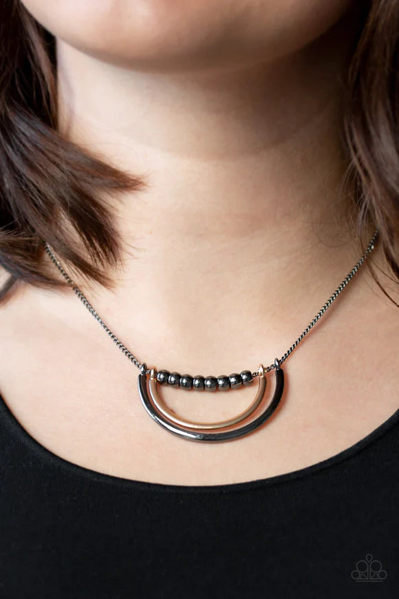 Paparazzi Accessories Artificial Arches - Black A strand of shiny gunmetal beads give way to bowing gold and gunmetal frames, creating an edgy pendant below the collar. Features an adjustable clasp closure. Sold as one individual necklace. Includes one pa